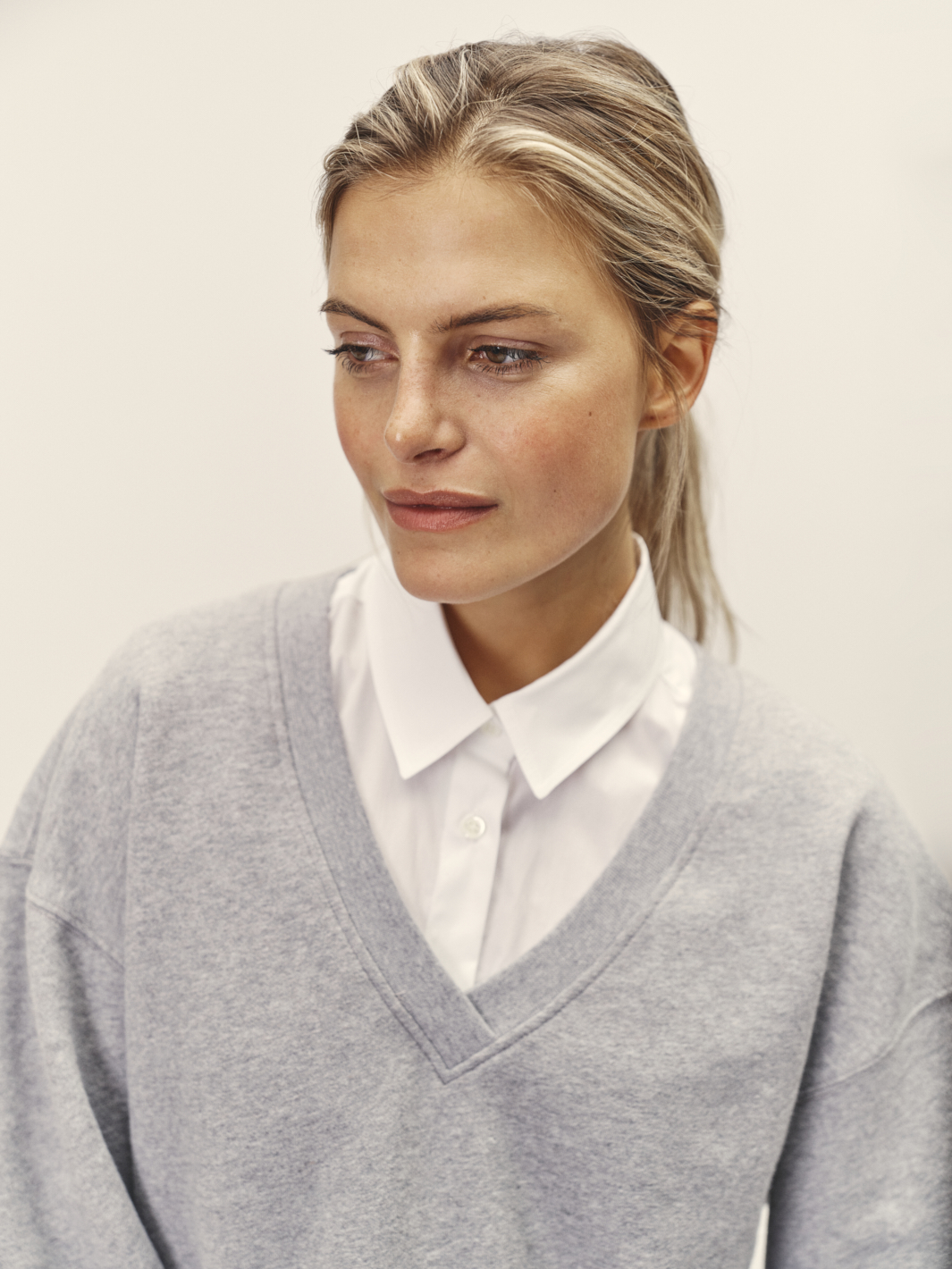 Nahaufnahme vom weiblichen Model mit weißen Hemd und hellgrauen Pulli darüber